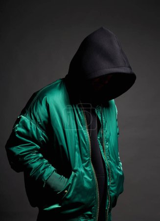 Photo for Stylish Man. Person in Black Hood and green bomber jacket. Trendy wear Boy in a hooded sweatshirt - Royalty Free Image