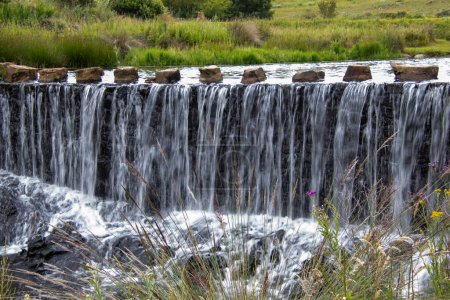 Photo for Water runs from a stream over the wall of a weir - Royalty Free Image