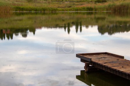 Photo for A dam with cloud reflection on the water and a wooden jetty - Royalty Free Image