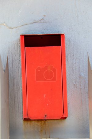 Foto de Buzón rojo de señal montado en una pared gris agrietada - Imagen libre de derechos