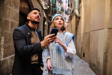Foto de Pareja de pareja de turistas perdidos localizándose con el teléfono móvil en la calle - Imagen libre de derechos