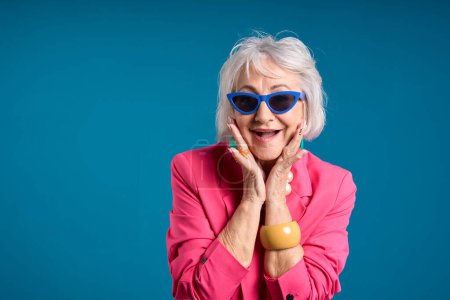 Lebendige Seniorin in rosa Jacke mit blauer Sonnenbrille