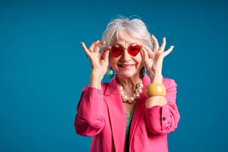 Femme âgée à la mode avec des lunettes de soleil en forme de coeur