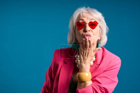 Elegant Senior Woman Blowing a Kiss in Heart Sunglasses