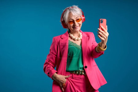 Femme âgée à la mode prenant Selfie avec écouteurs rouges
