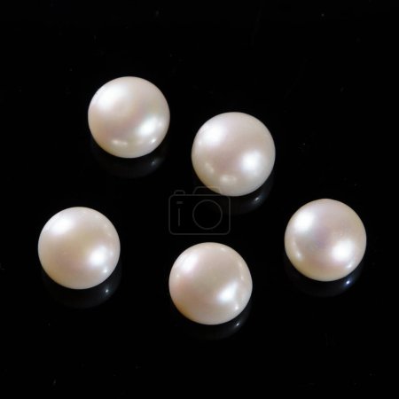 Natural pearls on a black background. White round pearls