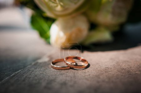 Photo for Golden wedding rings, in the background the bride's bouquet of multi-colored flowers. - Royalty Free Image