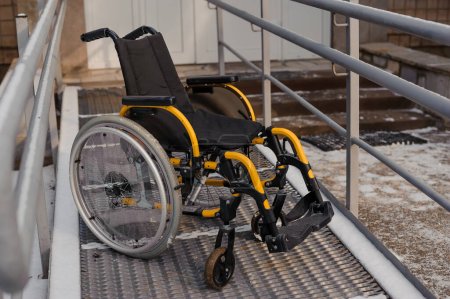 Foto de Empty wheelchair in the hospital on the ramp. Wheelchair close-up. Childrens wheelchair. - Imagen libre de derechos