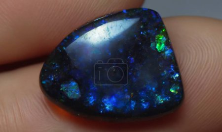 Photo for Natural gem black rainbow opal on brown background - Royalty Free Image