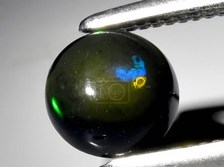 natural rainbow black opal gemstone on background