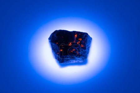 pierre gemme yooperlite naturelle dans la lumière UV sur fond blanc