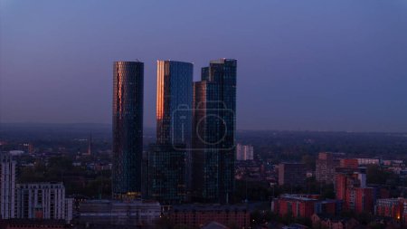 Foto de El atardecer captura la ciudad en una fase de transición, el cielo todavía sostiene la última luz a medida que los edificios comienzan a brillar desde dentro - Imagen libre de derechos