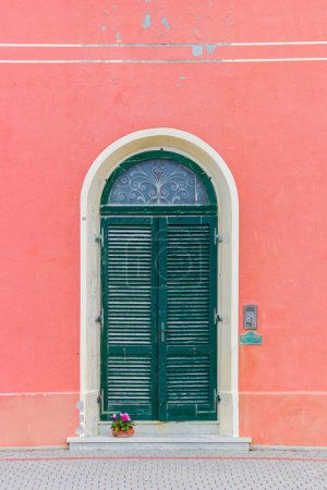 Pink house with a green door in Marina di Pisa, Italy