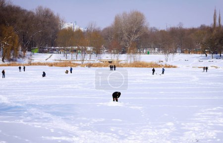 Foto de Pescadores pescan en el lago congelado en un día soleado de invierno - Imagen libre de derechos