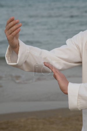 Téléchargez les photos : Homme pratiquant le tai chi au bord de la mer - en image libre de droit