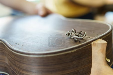 Téléchargez les photos : Doux focus d'artisan méconnaissable sculptant une partie pour guitare flamenco espagnole sur établi pendant le travail dans un atelier luthier - en image libre de droit
