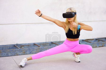 Photo for Full body of fit female in VR goggles performing kung fu fighting stance while practicing martial arts during virtual training outdoors - Royalty Free Image