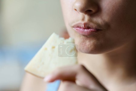 Téléchargez les photos : Gros plan de la récolte adolescent méconnaissable tenant tranches de fromage mangé à la maison - en image libre de droit