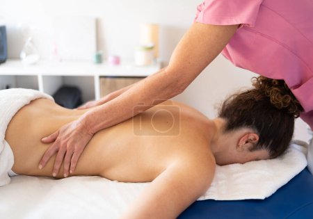 Photo for Side view of crop unrecognizable female massage therapist kneading back of patient lying on couch with towel during session relaxation and recreation concept - Royalty Free Image