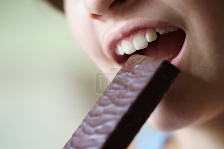 Photo for Crop unrecognizable teenage girl with mouth open about to eat healthy protein bar at home - Royalty Free Image