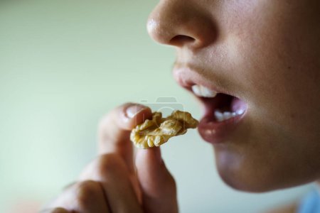 Foto de Cultivo irreconocible adolescente con la boca abierta a punto de comer deliciosa nuez en casa - Imagen libre de derechos