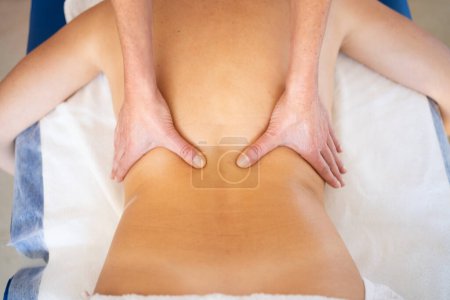 Photo for Top view of crop anonymous female massage therapist rubbing back with hands while giving professional treatment to patient in clinic - Royalty Free Image