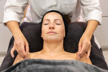 Foto de Cosecha esteticista haciendo masaje con cubo de hielo en el hombro del cliente femenino en el salón de belleza moderno durante el tratamiento del cuidado de la piel - Imagen libre de derechos