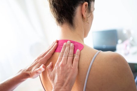 Photo for Back view of crop anonymous female therapist applying kinesiology tape on back of female patient during physiological massage in modern clinic - Royalty Free Image