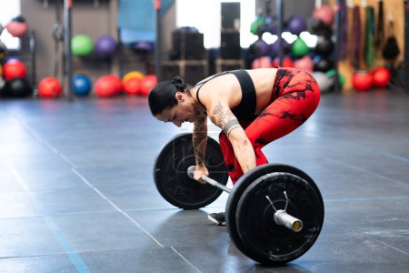 Photo for Horizontal photo of a sportive woman about to lift weight with bar in a gym - Royalty Free Image