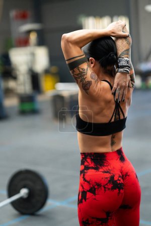 Photo for Rear view of a strong female athlete stretching after working out in a gym - Royalty Free Image