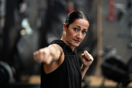 Photo for Portrait with focus on a concentrated female boxer throwing a jab while shadowboxing in the gym - Royalty Free Image