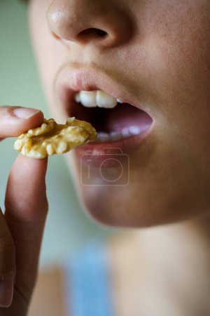 Foto de Primer plano de la cosecha chica adolescente anónima con la boca abierta a punto de comer deliciosa nuez en casa - Imagen libre de derechos