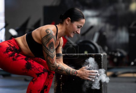 Photo for Magnesium dust floating from the hands of a sporty woman about to lift weights - Royalty Free Image