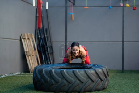 Foto de Deportiva mujer madura volteando una enorme rueda en un gimnasio de entrenamiento cruzado - Imagen libre de derechos