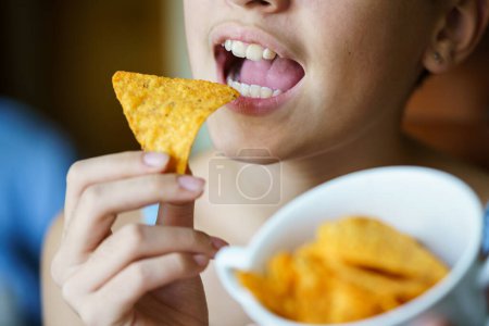Photo for Crop unrecognizable teenage girl with mouth wide open about to eat spicy tortilla chip at home - Royalty Free Image