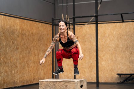 Foto de Mujer madura haciendo ejercicio saltando a la caja en un gimnasio de entrenamiento cruzado - Imagen libre de derechos