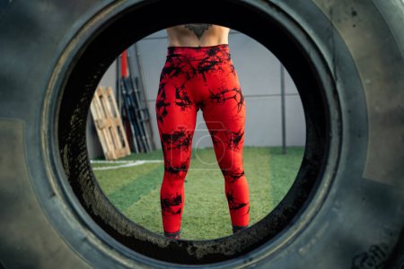 Téléchargez les photos : Vue à travers une roue des jambes fortes d'une femme dans une salle de gym - en image libre de droit