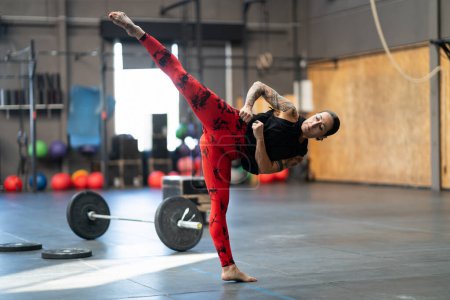 Téléchargez les photos : Flexible sportive femme mature coups de pied dans l'air dans la salle de gym - en image libre de droit