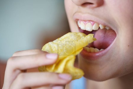 Photo for Crop unrecognizable teenage girl with mouth wide open eating crunchy potato chips at home - Royalty Free Image