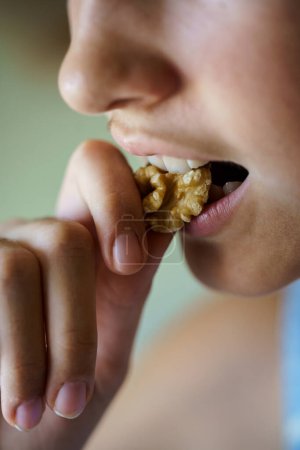 Téléchargez les photos : Gros plan de la récolte anonyme jeune fille mangeant du grain de noix sain à la maison - en image libre de droit