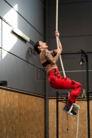 Photo for Vertical photo of a sportive mature woman exercising with a rope in a cross training gym - Royalty Free Image