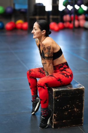 Photo for Vertical side view photo of a mature athlete resting sitting on a box in a gym - Royalty Free Image