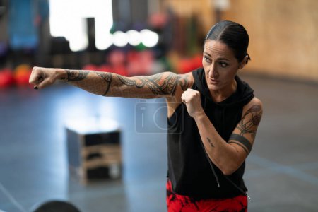 Téléchargez les photos : Gros plan d'une femme sportive mature qui fait de la boxe dans un gymnase de cross-training - en image libre de droit