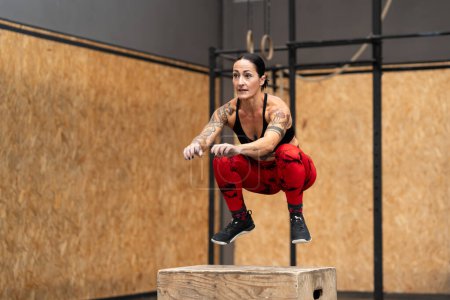Photo for Motion photo of a strong sportive woman jumping into box in a gym - Royalty Free Image