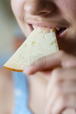 Téléchargez les photos : Gros plan de la récolte heureux anonyme adolescent fille mordre tranche de fromage frais à la maison - en image libre de droit