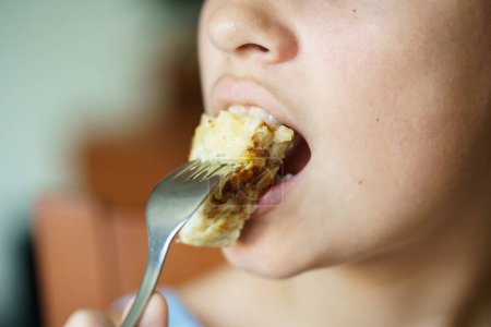 Téléchargez les photos : Recadrer adolescente anonyme manger omelette fraîche délicieuse pomme de terre espagnole de fourchette à la maison - en image libre de droit