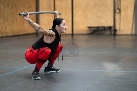 Photo for Side view photo with copy space of a mature woman squatting with a bar in a gym - Royalty Free Image