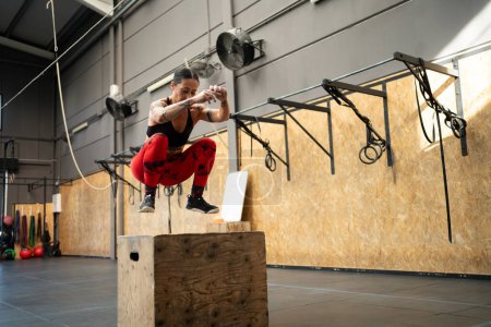 Foto de Fotografía horizontal con espacio de copia de una mujer saltando en una caja en un gimnasio de entrenamiento cruzado - Imagen libre de derechos