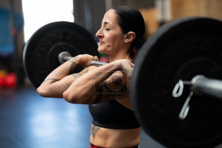 Téléchargez les photos : Femme forte sportive faisant un effort pour soulever des poids dans un gymnase d'entraînement croisé - en image libre de droit