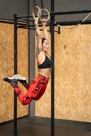 Vertikales Foto einer reifen Athletin, die mit olympischen Ringen in einer Turnhalle trainiert